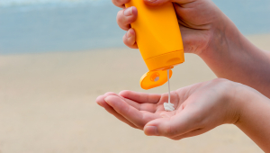Someone's hands applying sunscreen at the beach